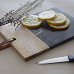 Sliced lemons on a wooden and slate cutting board with a knife and lavender flowers.