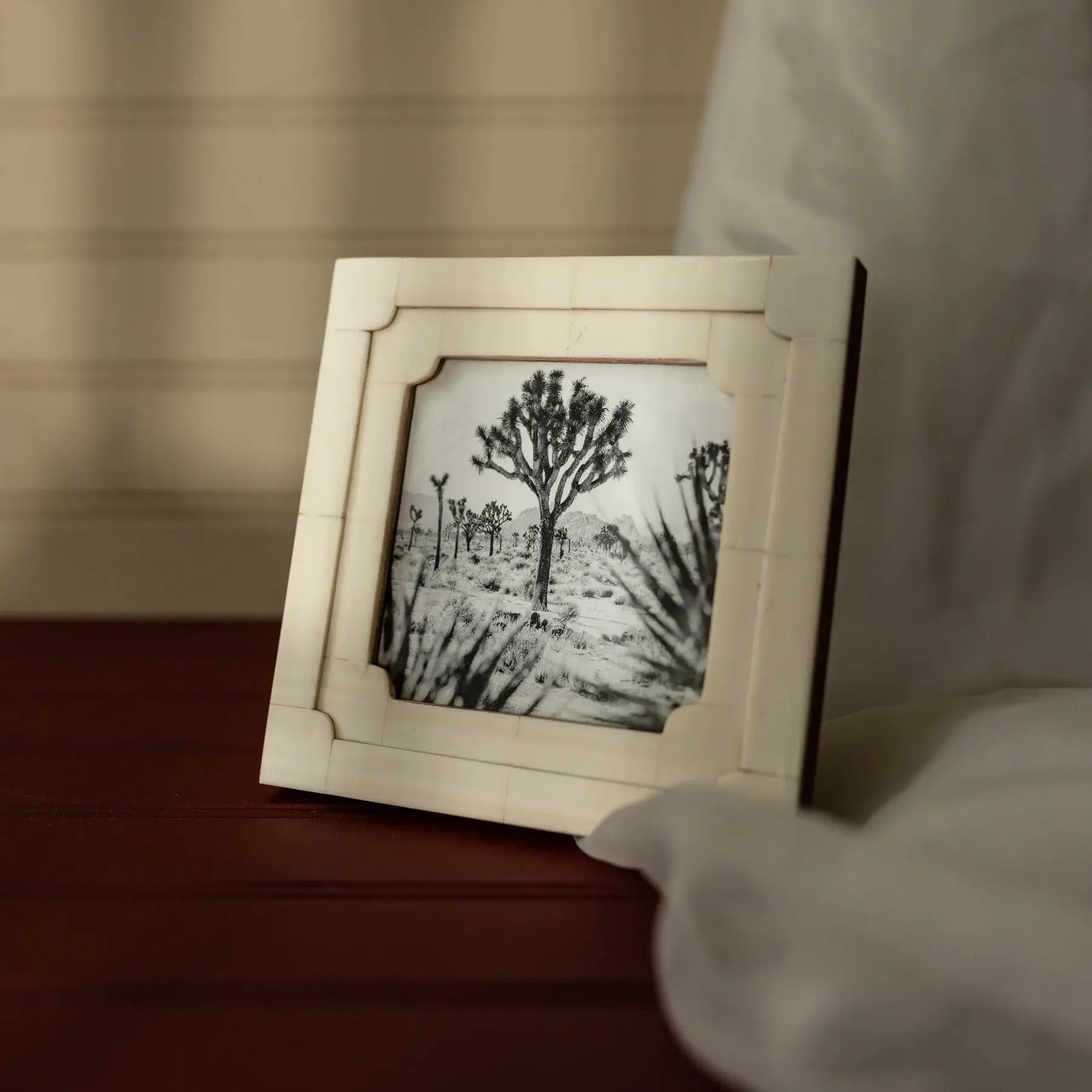 Framed artwork of a tree on a wooden surface with a blurred background