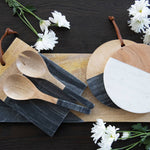 Wooden spoons and cutting boards on a dark surface with white flowers.