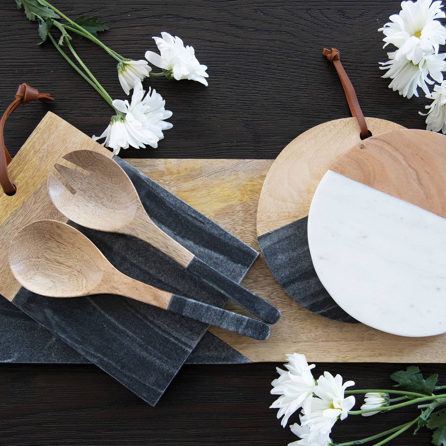 Wooden spoons and cutting boards on a dark surface with white flowers.