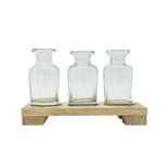 Three clear glass bottles on a wooden stand against a white background