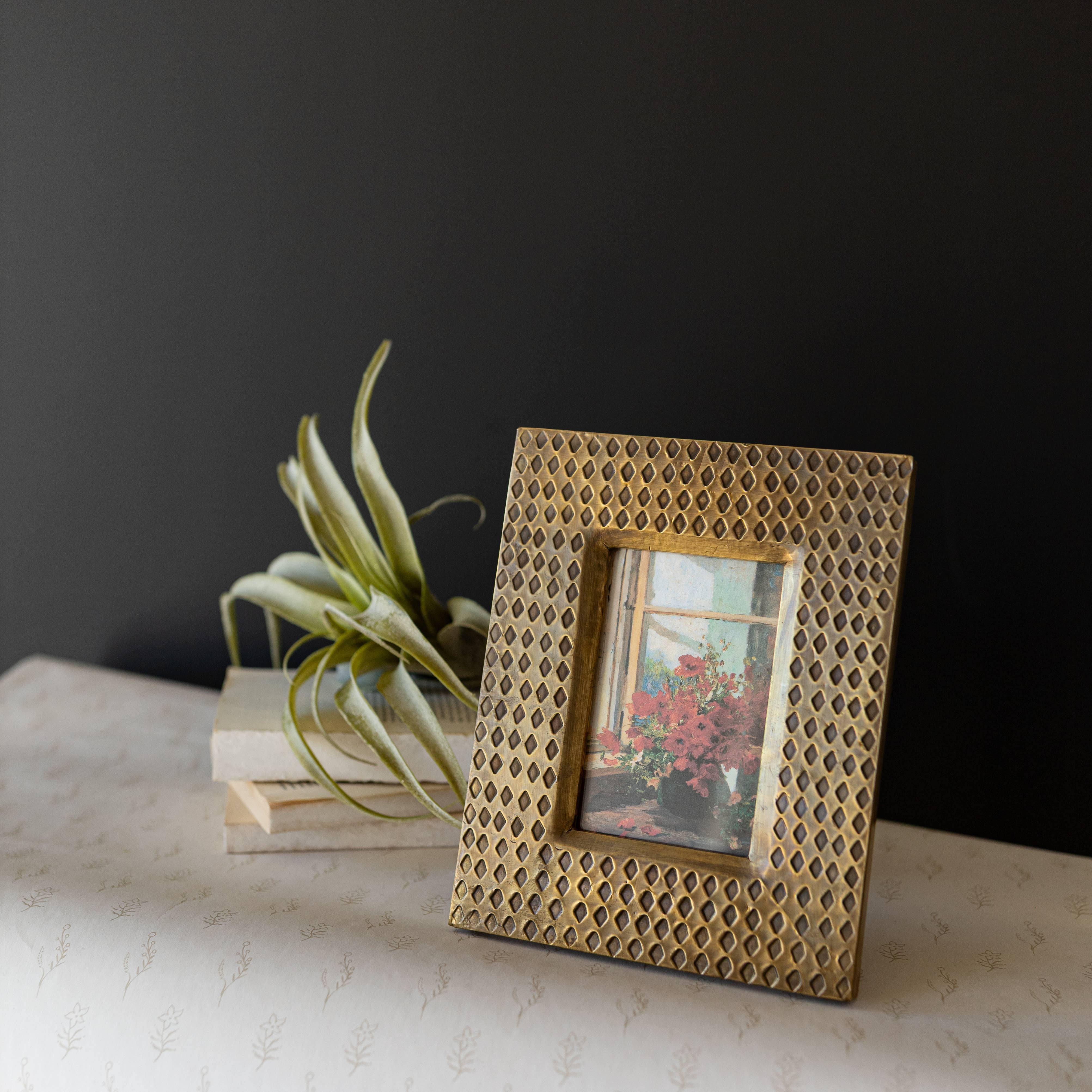 Decorative gold photo frame with a plant and books in the background