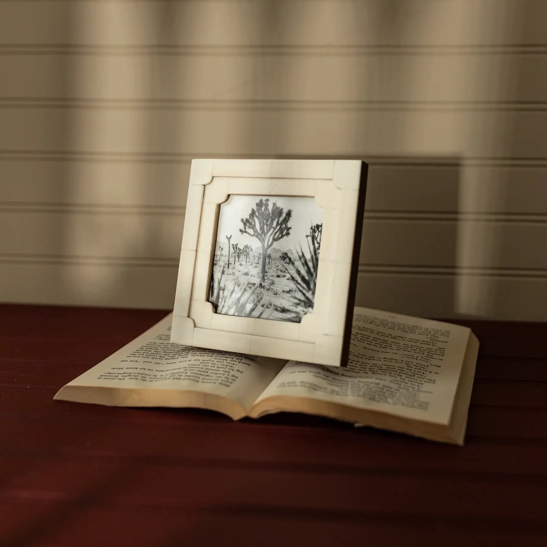 Open book with a framed picture of a tree on a wooden surface