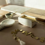 Brass bracelet on a wooden surface with a decorative box and small bowl in the background