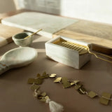 Brass bracelet on a wooden surface with a decorative box and small bowl in the background
