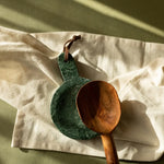 Green marble cutting board and wooden spoon on a light fabric surface