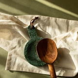 Green marble cutting board and wooden spoon on a light fabric surface