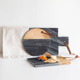 Set of marble and wood cutting boards with a white napkin on a light background
