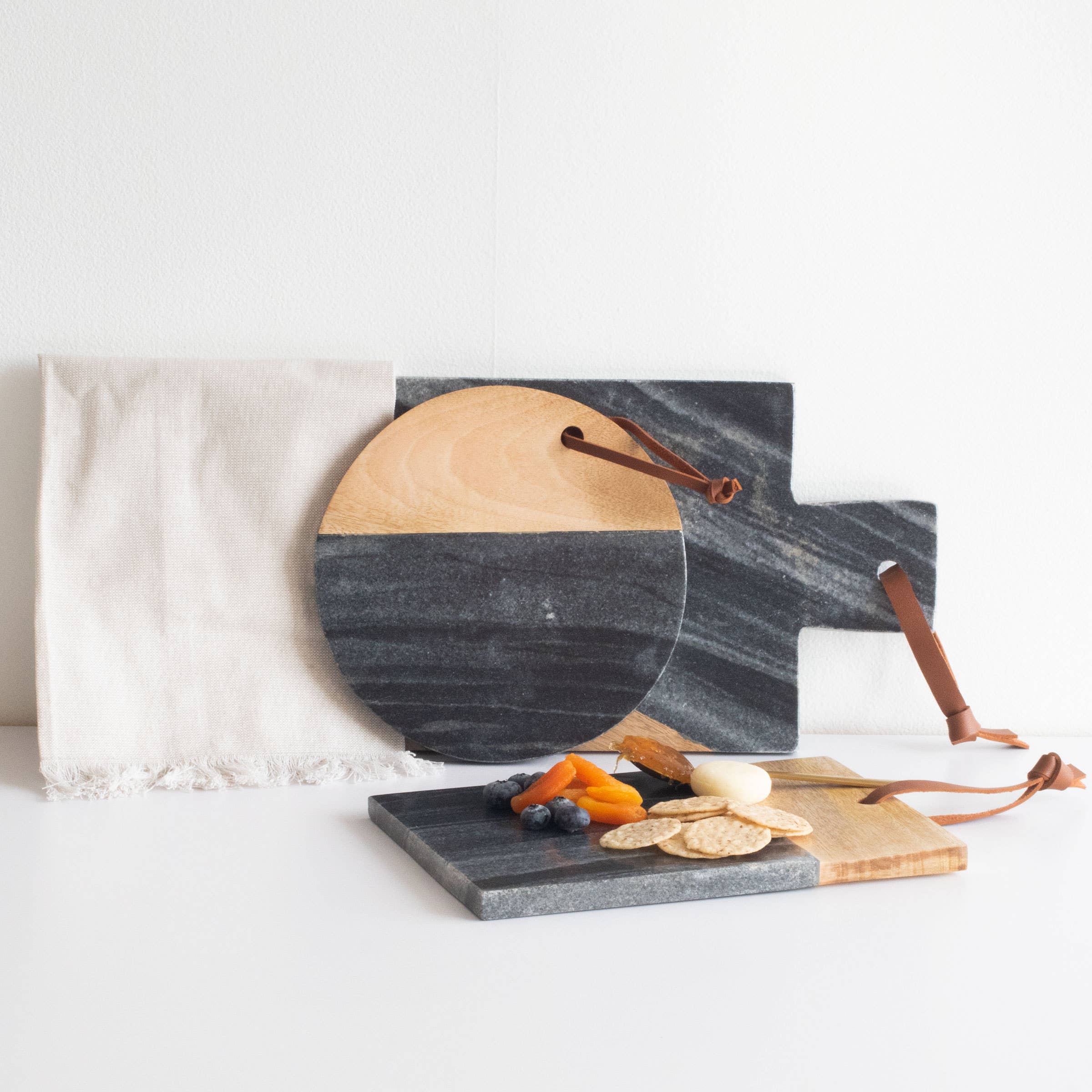 Set of marble and wood cutting boards with a white napkin on a light background