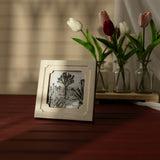Framed artwork on a wooden surface with tulips in the background