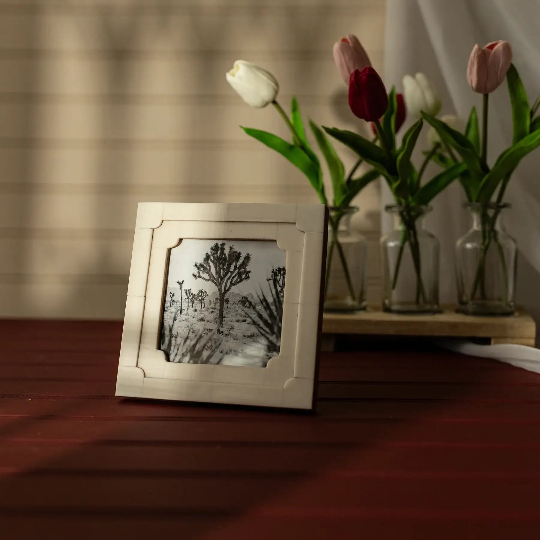 Framed artwork on a wooden surface with tulips in the background