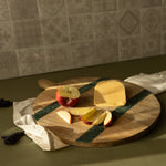 Wooden cutting board with cheese and apples on a kitchen counter.