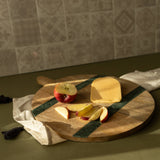 Wooden cutting board with cheese and apples on a kitchen counter.
