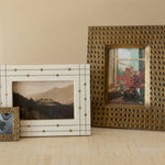 Three decorative picture frames on a wooden surface with a neutral background