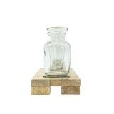 Clear glass vase on a wooden base against a white background