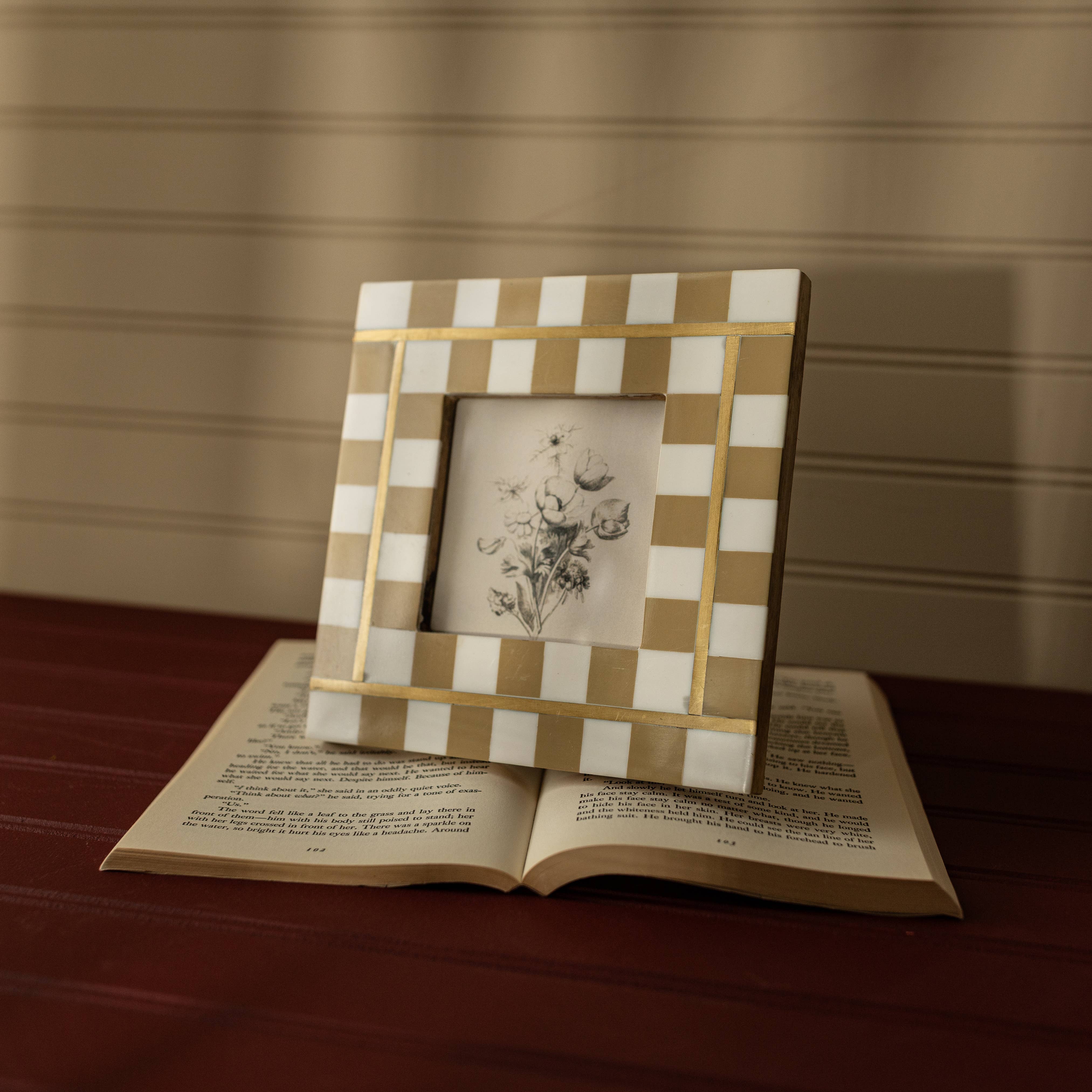 Checkered photo frame on an open book with a floral illustration