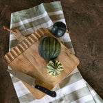 Wooden cutting board with vegetables on a striped cloth