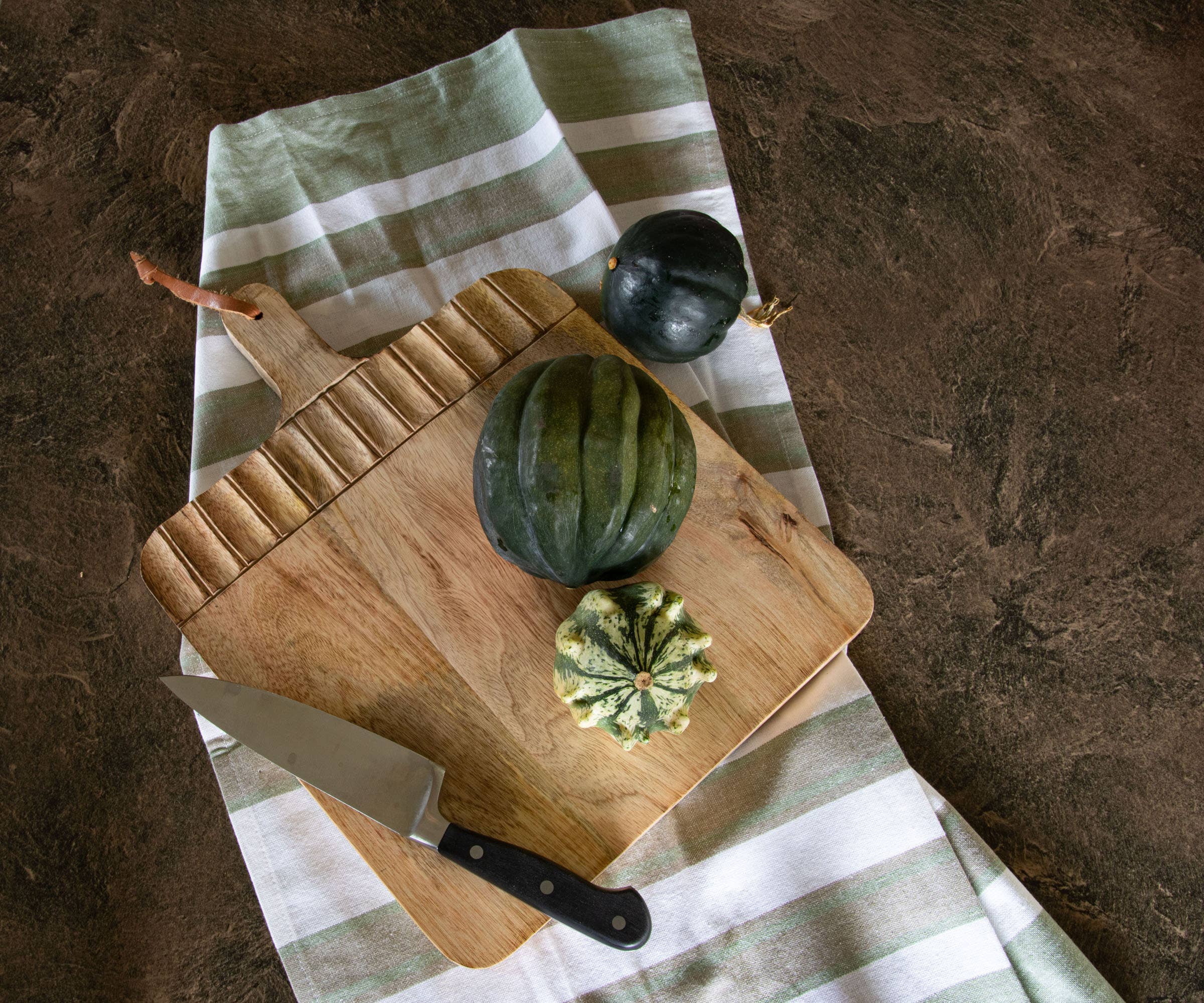 Wooden cutting board with vegetables on a striped cloth