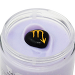 Jar of purple cream with a black stone featuring a yellow symbol on a white background