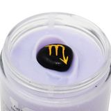 Jar of purple cream with a black stone featuring a yellow symbol on a white background