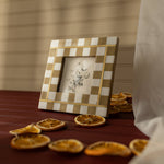 Decorative checkered frame with a small picture on a table with dried oranges.