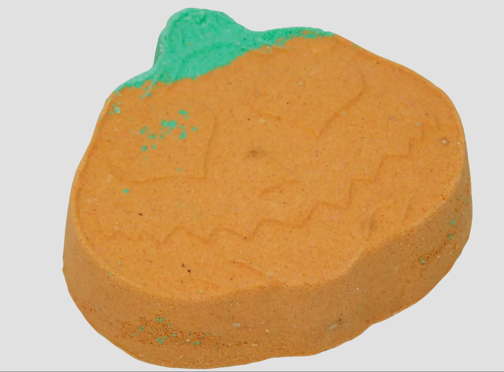 Pumpkin-shaped bath bomb with green top on a white background