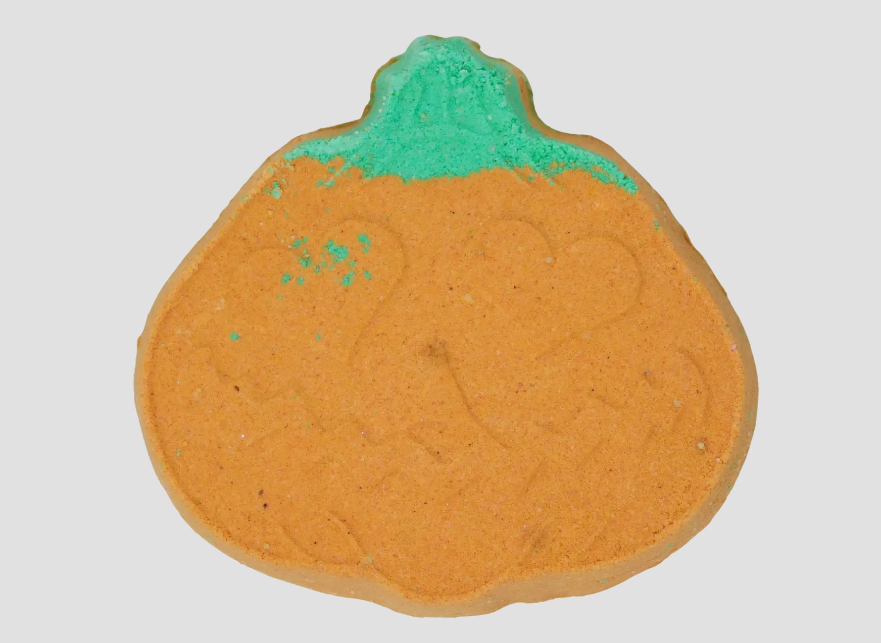 Pumpkin-shaped bath bomb with green top on a white background