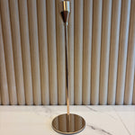 Gold Taper Candle Holder with metallic finish on a marble wall.