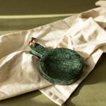 Green marble spoon rest on a beige fabric surface