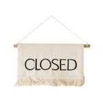 Fabric sign with 'CLOSED' text hanging on a white background