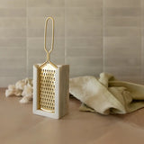 Decorative gold grater on a beige surface with a neutral background
