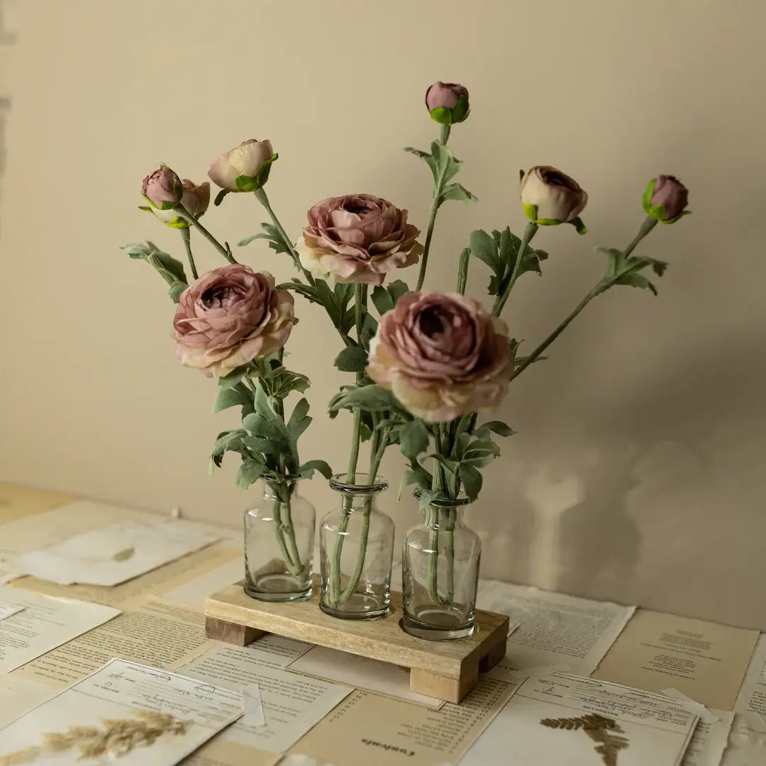 Bouquet of pink flowers in glass vases on a wooden stand with papers below