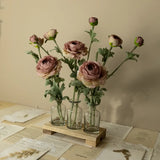Bouquet of pink flowers in glass vases on a wooden stand with papers below