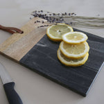 Sliced lemons on a dark slate surface with a wooden board and knife in the background.