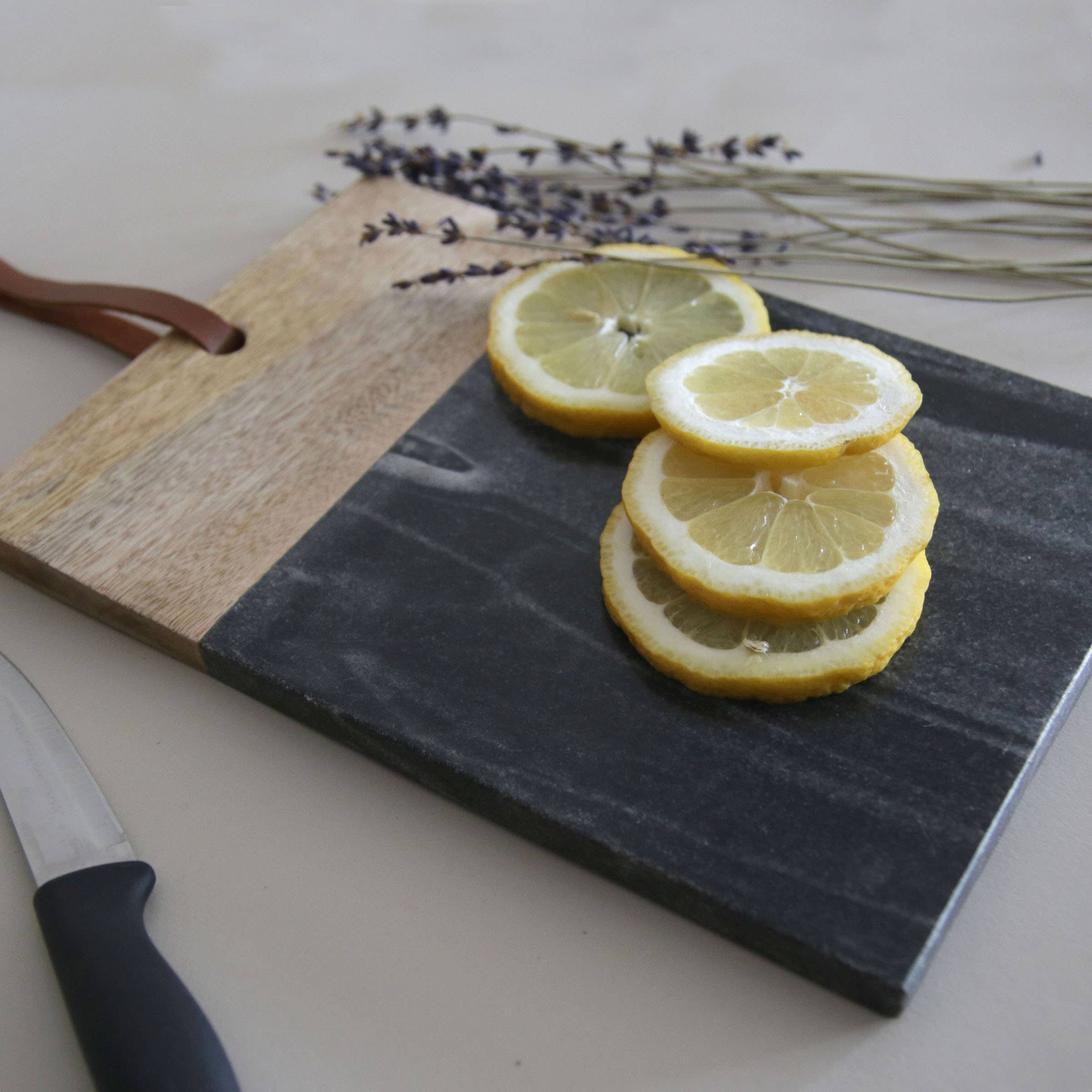 Sliced lemons on a dark slate surface with a wooden board and knife in the background.